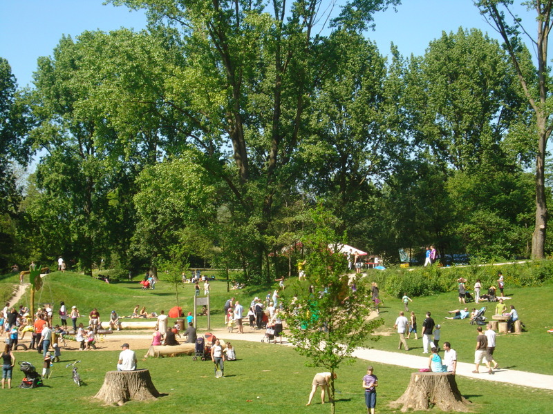 Vue du parc urbain à Villeneuve d'Ascq en été avec des familles qui profitent des jeux pour enfants