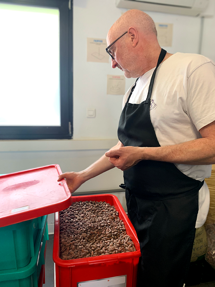 Laurent ouvre une caisse de cacao non torrefié dans l'atelier du Hillbar Lab